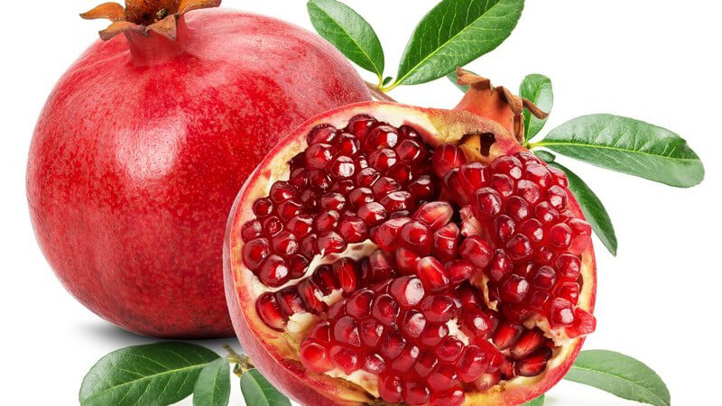 Ganzer und halbierter Granatapfel vor weißem Hintergrund
