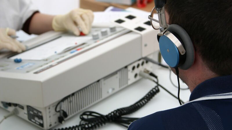 Rückenansicht Patient mit Kopfhörern beim Hörtest