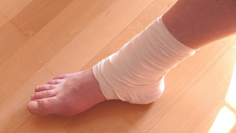 Nackter bandagierter Fuß auf Laminatboden