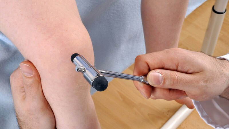 Arzt mit Reflexhammer an Knie von Kind