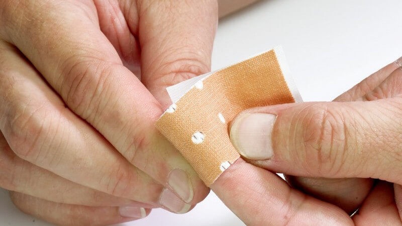 Zwei Männerhände, Pflaster wird auf linken Zeigefinger geklebt