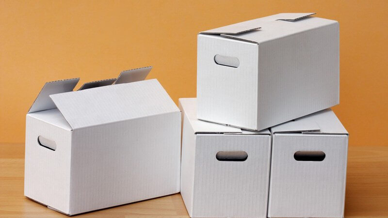 Kleine weiße Kartons auf Laminatboden, gelbe Wand