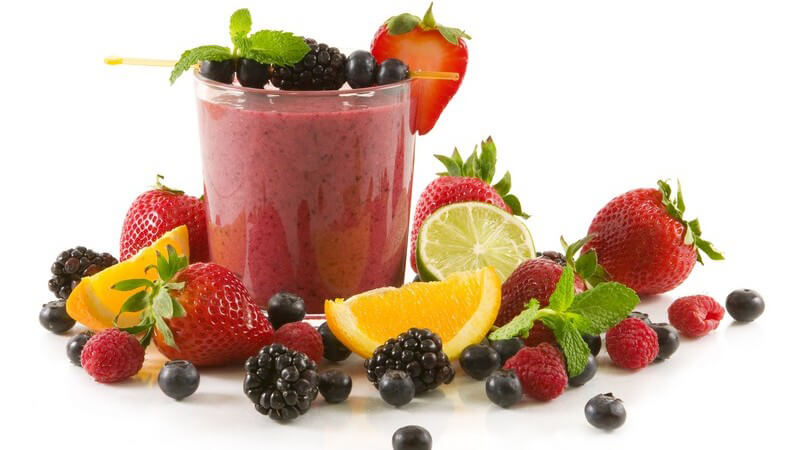 Früchte Smoothie umgeben von frischem Obst auf weißem Hintergrund