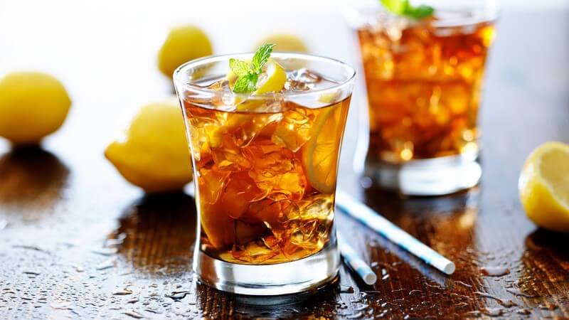 Eisteegläser mit viel Eis und Zitrone auf einem Holztisch