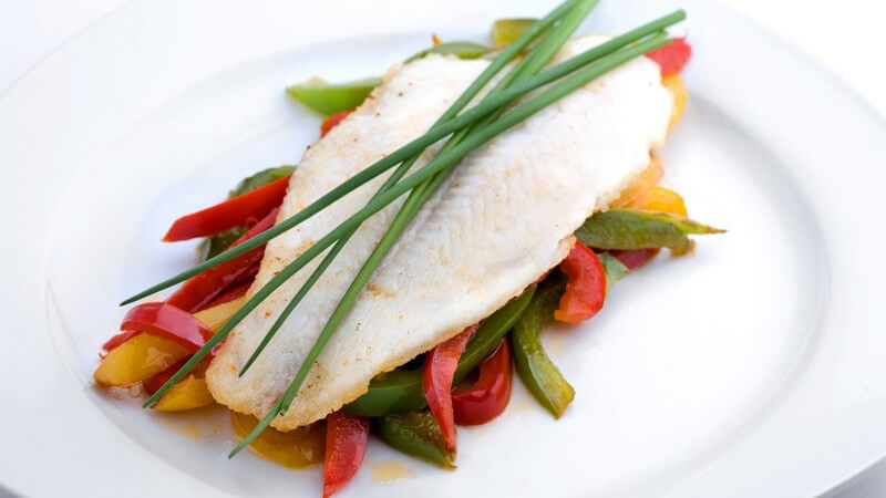 Schön angerichtetes Fischfilet mit Schnittlauch auf buntem Gemüse