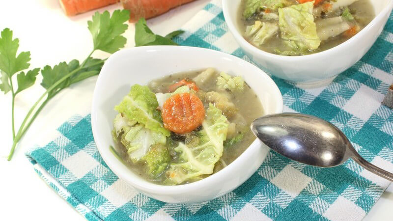 Zwei kleine Suppenteller mit Wirsingeintopf auf kariertem Platzdeckchen