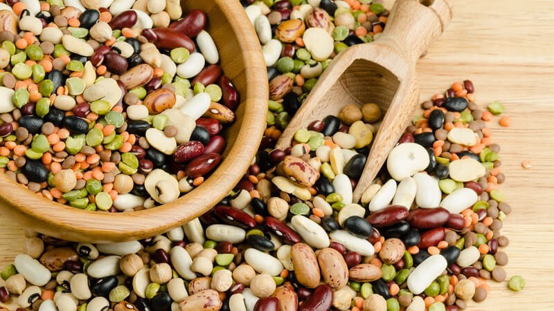 Verschiedene Hülsenfrüchte auf Holztisch und in Holzschale