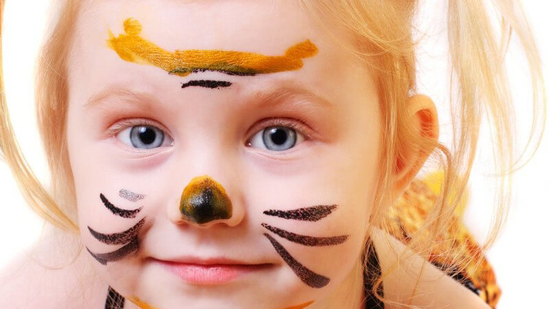 Kleines blonde Mädchen als Tiger verkleidet und geschminkt