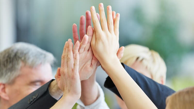 High Five für Erfolg im Beruf - Mitarbeiter in Geschäftskleidung klatschen ab