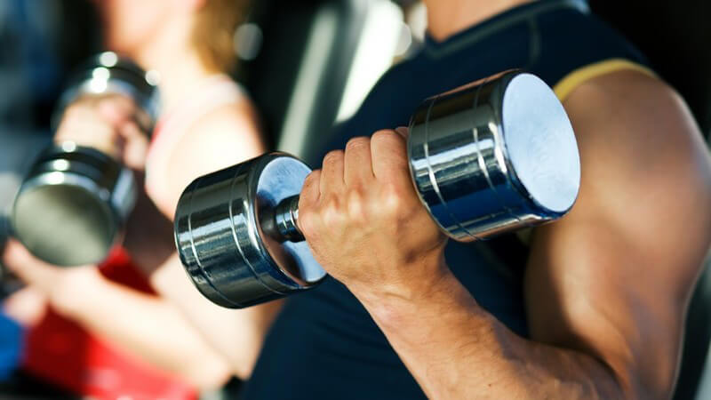 Muskulöser linker Arm mit Kurzhantel