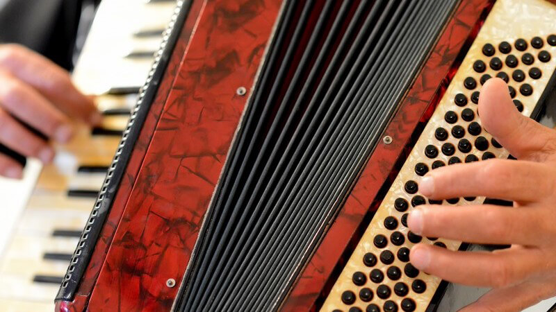 Hände spielen auf einem roten Akkordeon