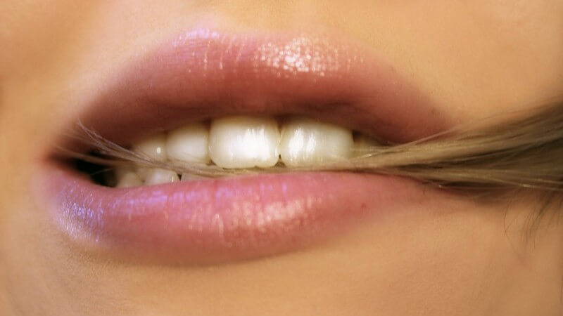 Haare - Geschminkter Kussmund mit blonder Haarsträhne zwischen den Zähnen