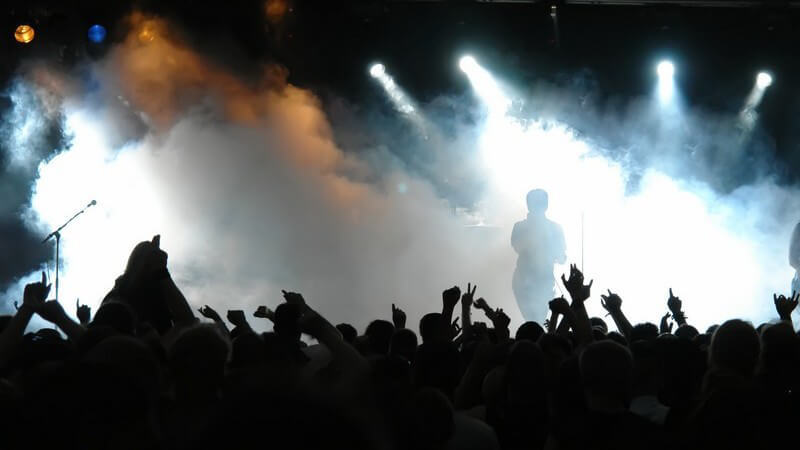 Jubelndes Publikum vor Bühne mit Musikern, Nebel
