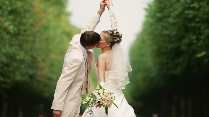 Küssendes Brautpaar, im Hintergrund schöne Landschaft