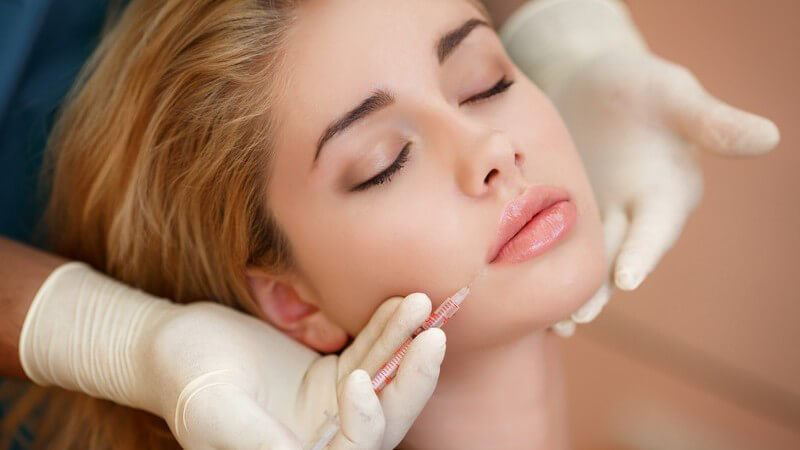 Junge Frau lässt sich Botox in die Lippe injizieren