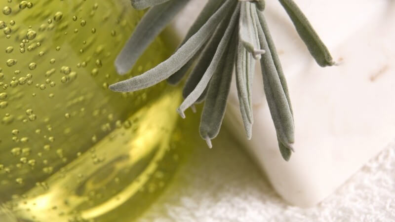 Nahaufnahme Flasche mit Massageöl, Seife, Kräuter auf weißem Handtuch