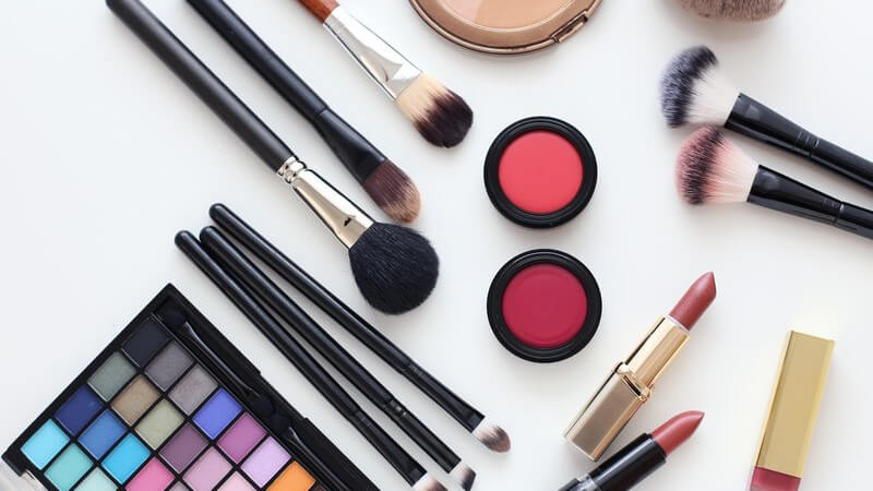 Sammlung diverser Kosmetika wie Make-up, Pinsel und Lippenstifte