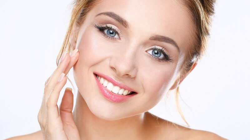 Portrait einer hübschen Frau, den Kopf leicht geneigt, die rechte Hand berührt sanft das Gesicht