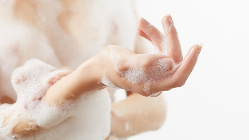 Arm und Oberkörper einer Frau voller Badeschaum