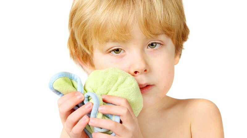 Kleiner Junge kühlt sein Kinn und seine Lippe, weißer Hintergrund