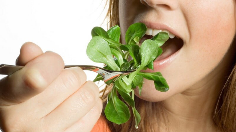 Nahaufnahme blonde Frau isst frischen Feldsalat