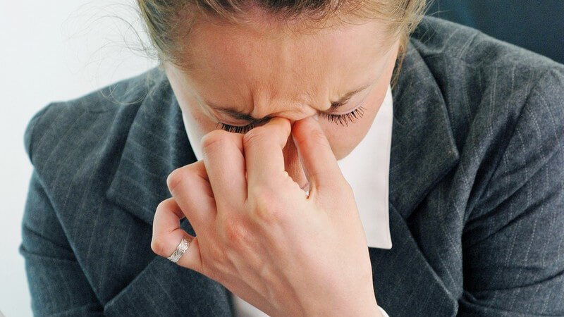 Geschäftsfrau vor Notebook ist müde, hält Hand vor Gesicht