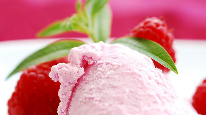 Erdbeer- oder Himbeereis, daneben frische Himbeeren