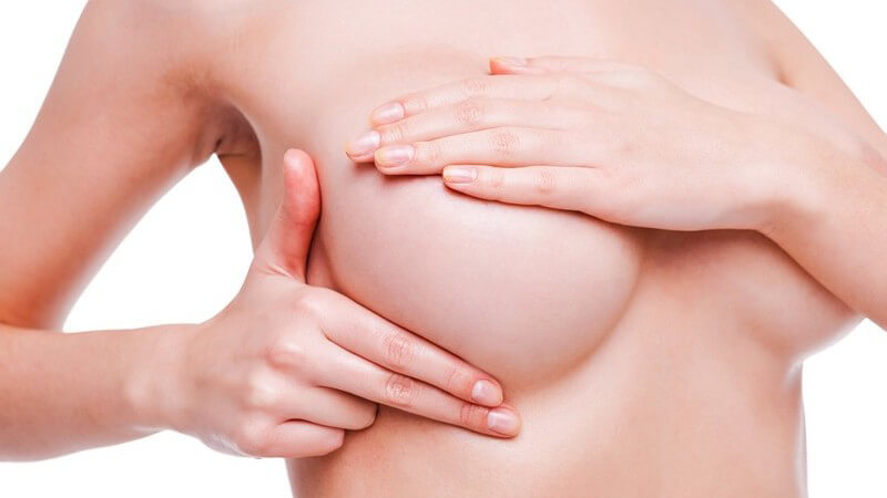 Frau tastet ihre rechte Brust ab