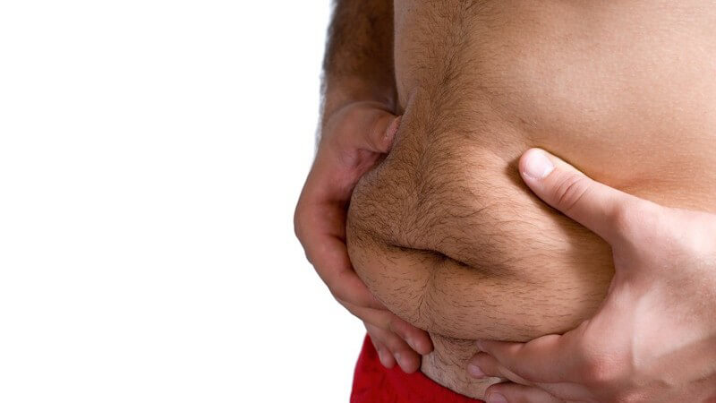 Bauch eines übergewichtigen Mannes, er drückt Bauchspeck vorne zusammen