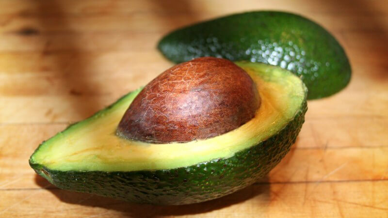 Aufgeschnittene Avocade auf Holzbrett