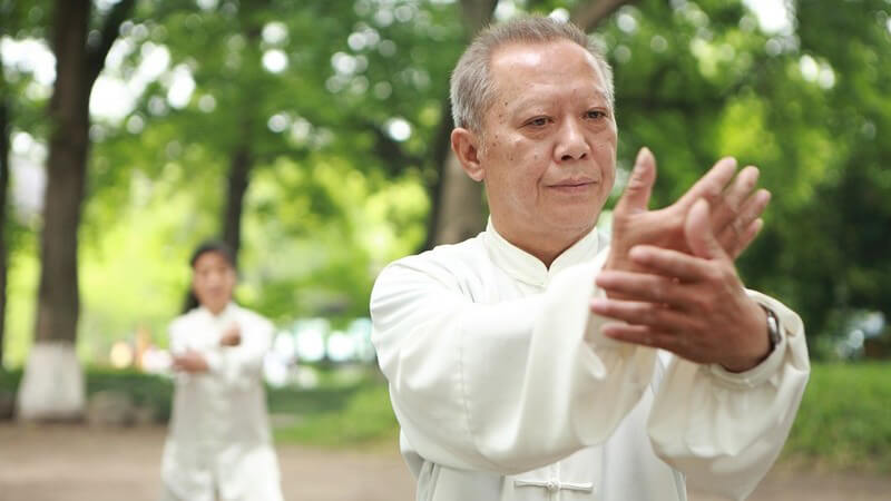 Zwei Sportler machen draußen Tai Chi