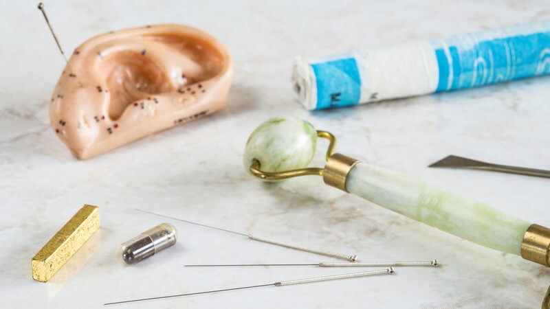 Ohrmodell mit Akupunkturpunkten, Moxazigarre, Akupunkturnadeln und anderes Zubehör