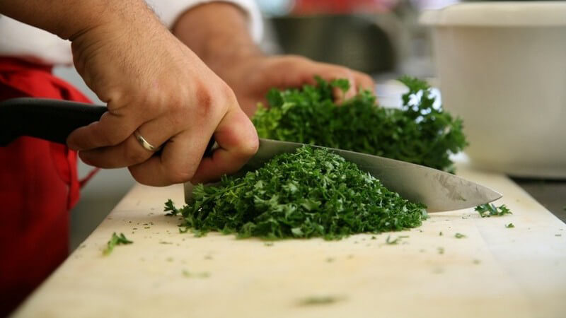 Kochen - Koch zerhackt Petersilie auf Schneidebrett