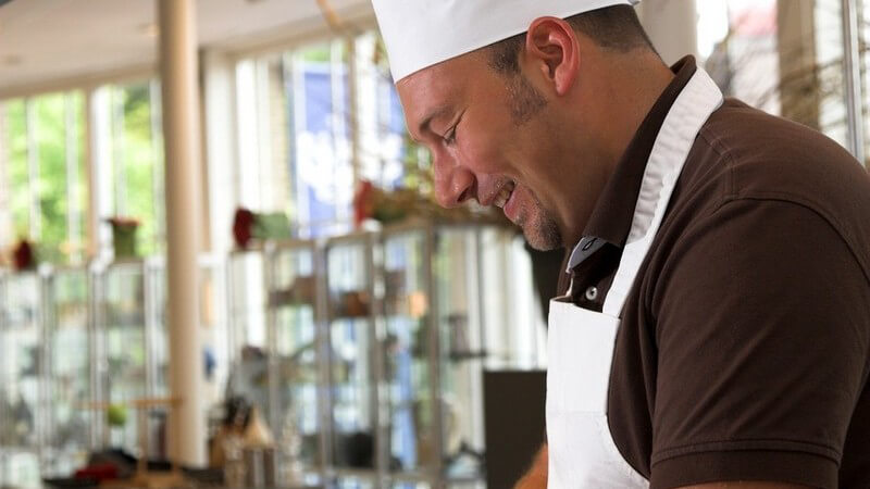 Kochen - Mann mit weißer Kochmütze und Schürze