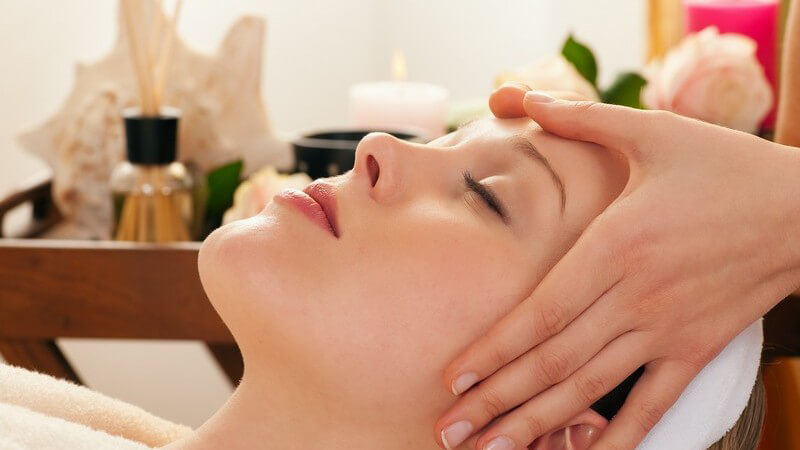 Junge Frau auf Liege bekommt Gesichtsmassage