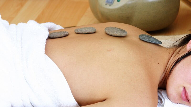Frau liegt entspannt auf Bauch, Hot Stones auf dem Rücken