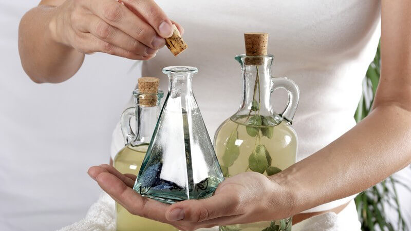 Drei kleine Flaschen aus Glas mit Massageöl auf weißem Handtuch