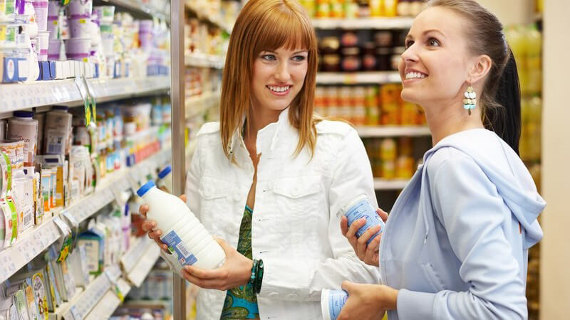 Zwei lächelnde Frauen vor Regal im Supermarkt