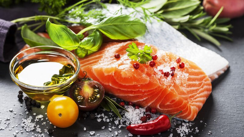 Rohes Lachsfilet mit frischen Kräutern auf schwarzem Untergrund