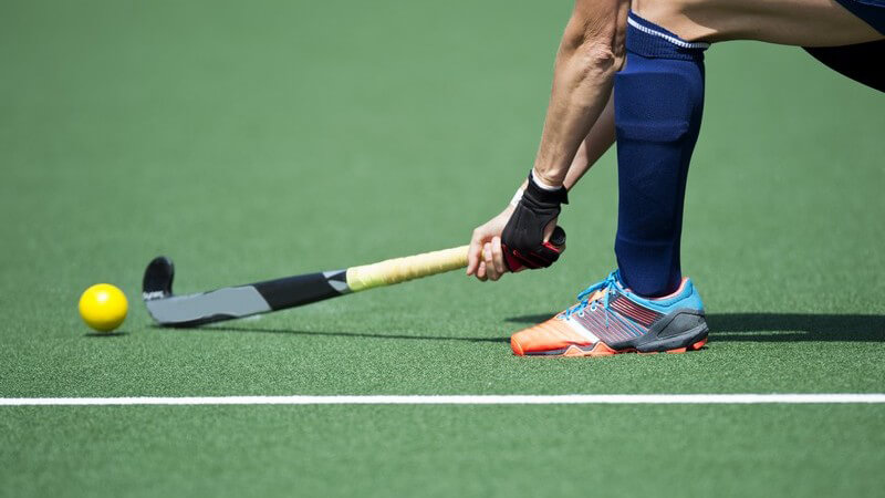 Feldhockeyspieler beim Passen eines gelben Balls