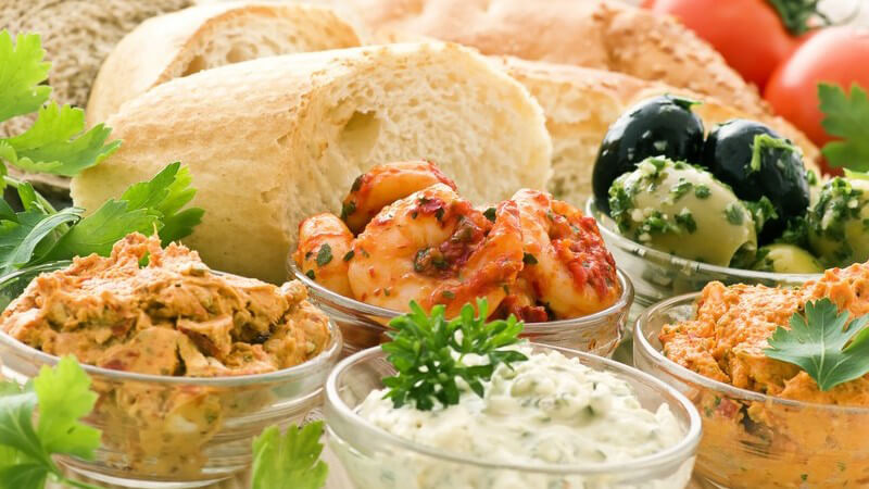 Glasschälchen mit verschiedenen Dips, dazu Baguette