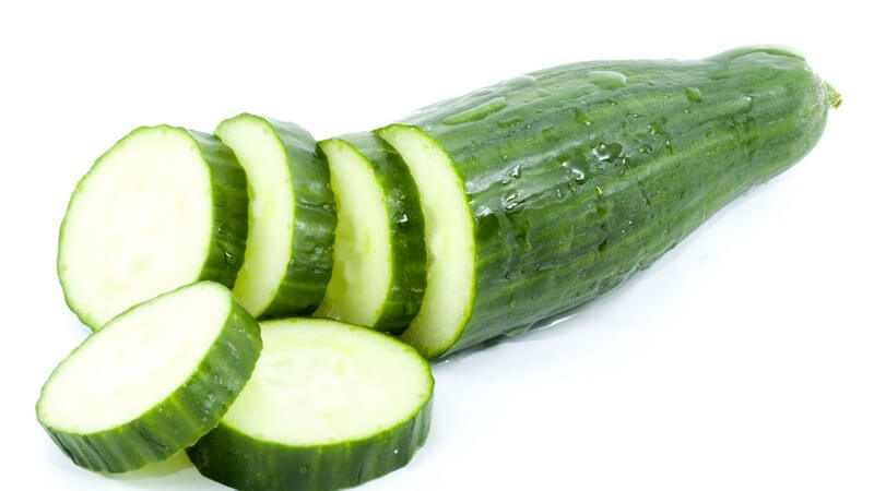 Frische Salatgurke, zum Teil geschnittene Scheiben auf weißem Hintergrund