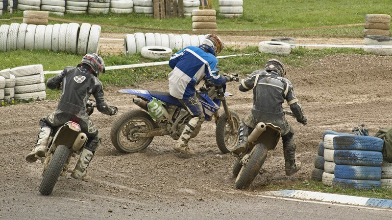 Drei Motorradfahrer beim Motocross