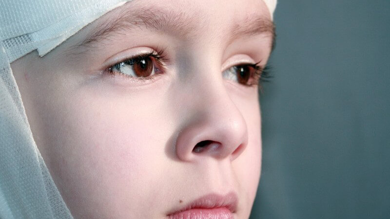 Gesicht eines traurigen kleinen Jungen mit Verband um den Kopf