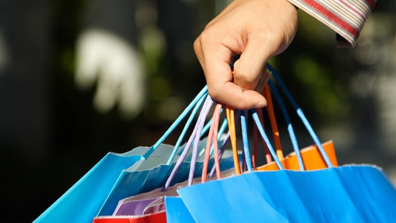 Hand trägt mehrere Einkaufstüten