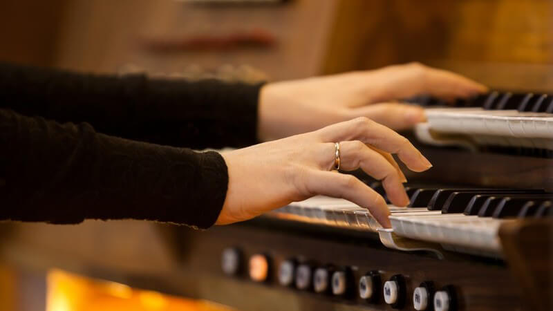 Hände einer Frau spielen auf einer Orgel