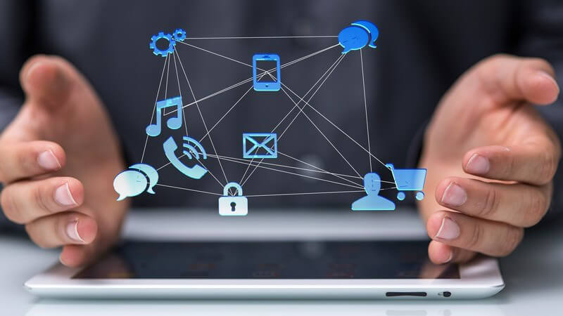 Hände eines Geschäftsmanns über einem Tablet, darüber moderne Mediensymbole, Kommunikation