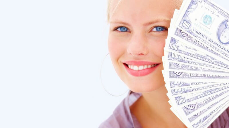 Blonde Frau lächelt in Kamera, hält Geldscheine vor Gesicht