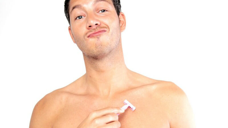 Junger, dunkelhaariger Mann mit nacktem Oberkörper beim Rasieren der Brust