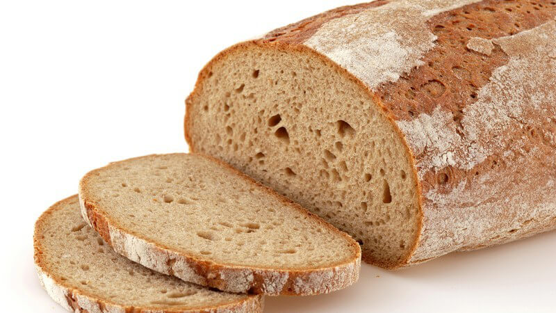 Backen - Dunkler Brotlaib mit zwei abgeschnittenen Brotscheiben